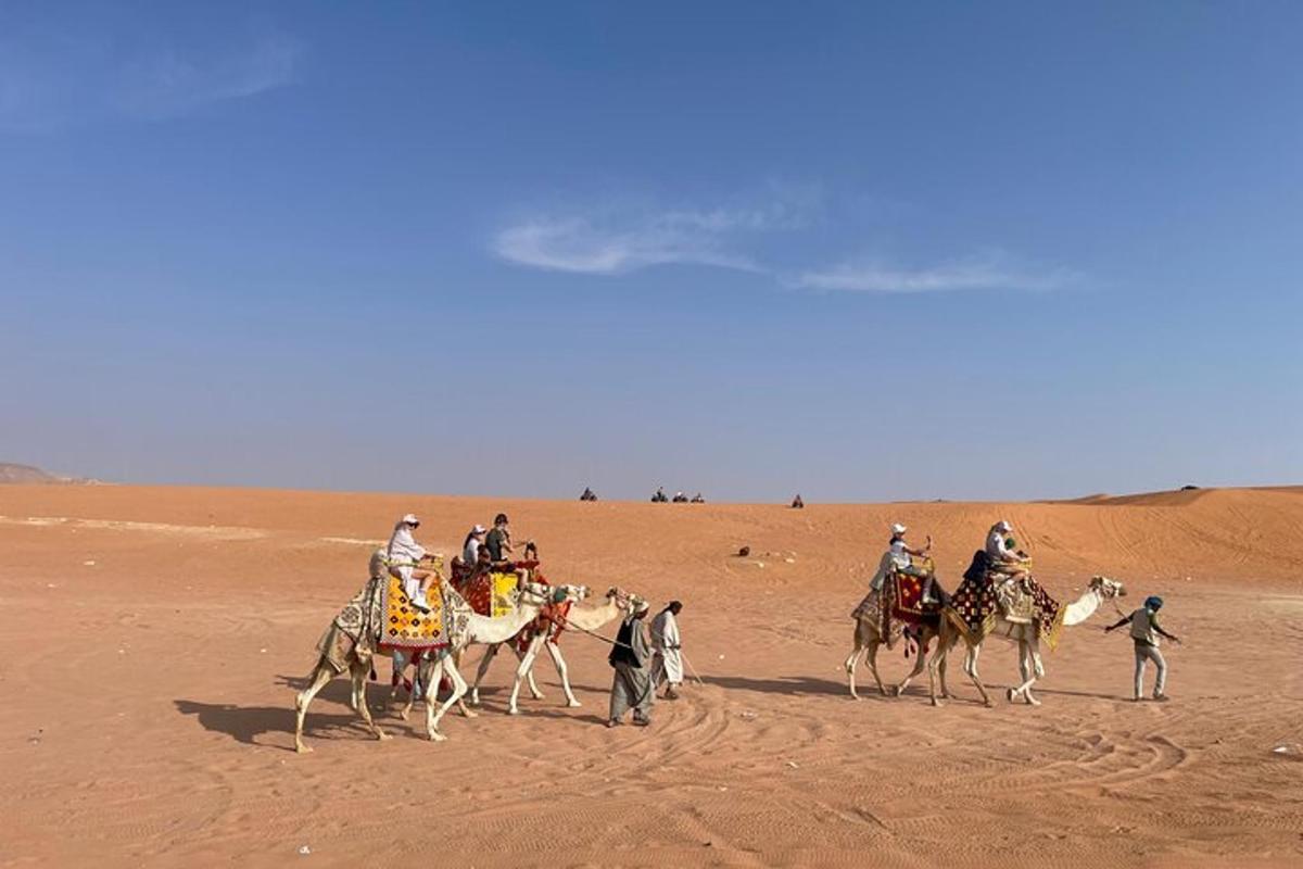 un gruppo di persone a cavallo di cammelli nel deserto