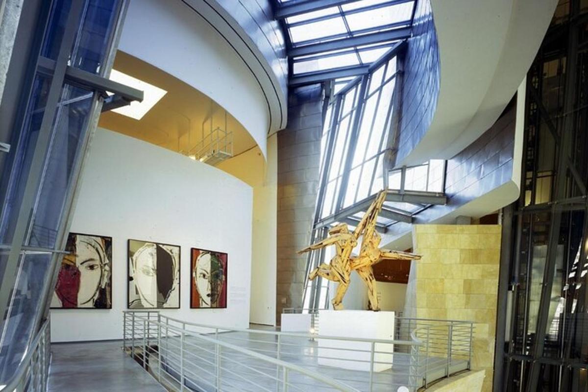 a museum with a glass hallway with paintings on the wall