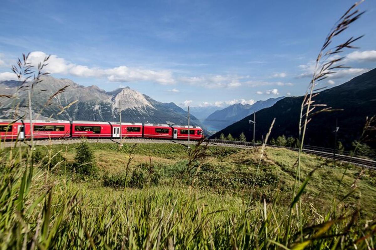 un tren roșu și alb pe o linie în munți