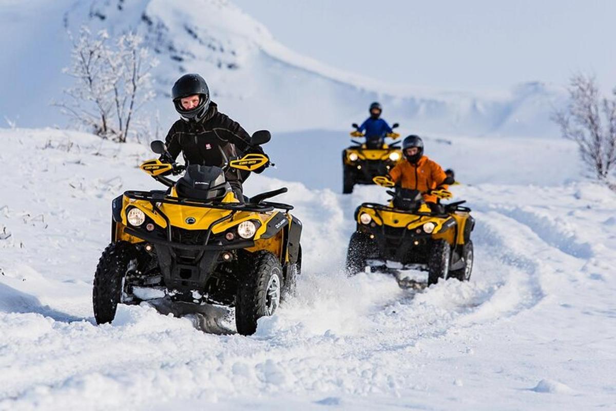 en grupp människor som kör fyrhjulingar i snön