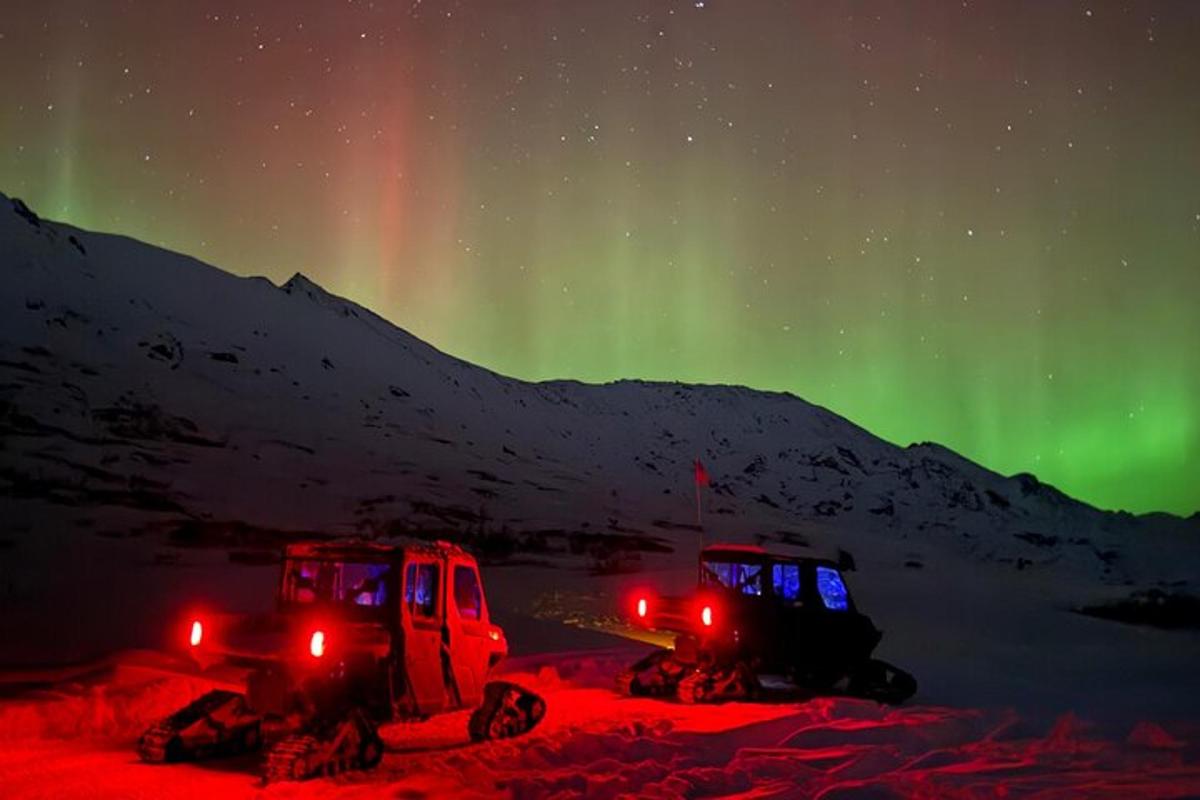 dos camions aparcats a la neu sota les aurores boreals