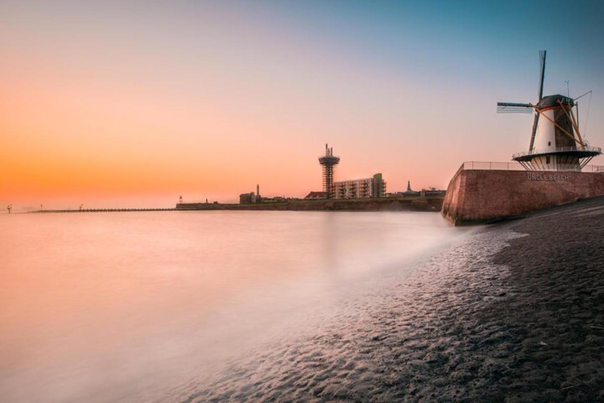 ein Sonnenuntergang über einem Gewässer mit einer Windmühle