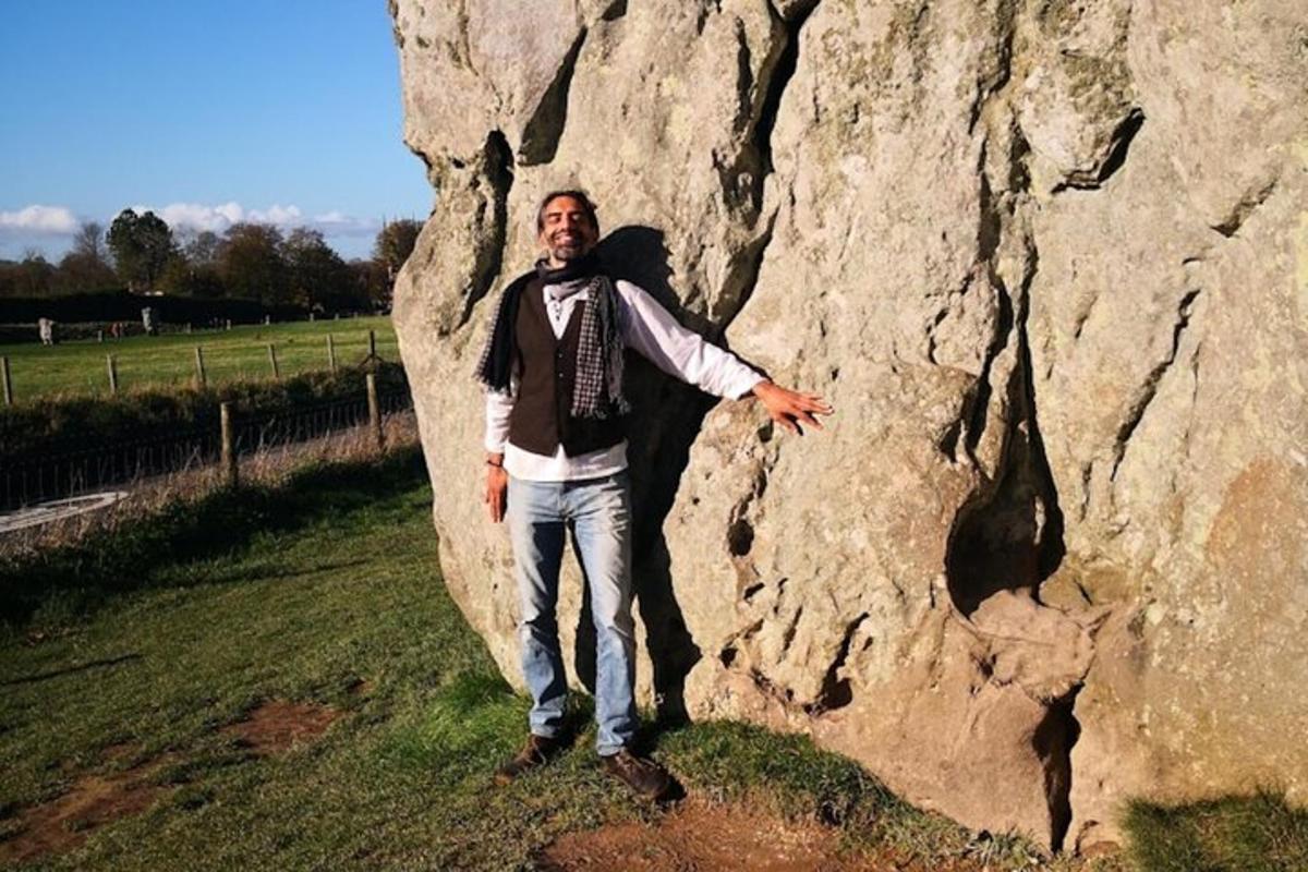 um homem parado ao lado de uma grande rocha