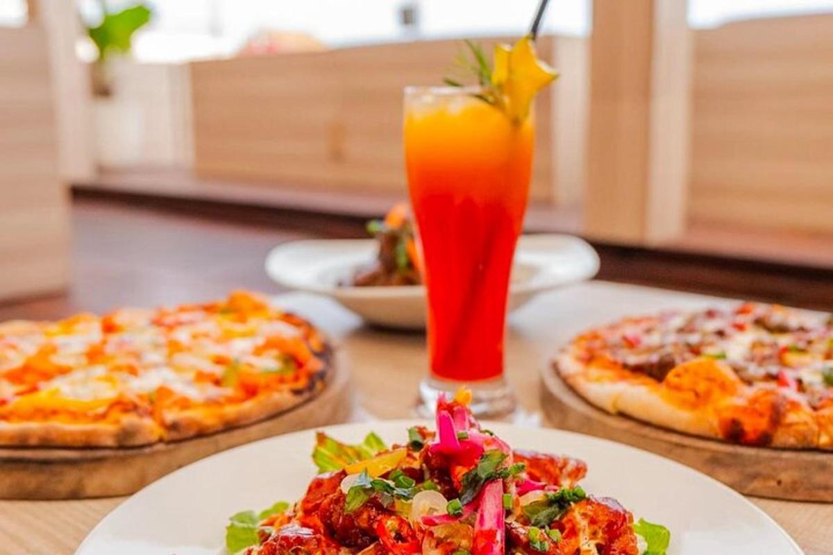 a table with two pizzas and a drink on it
