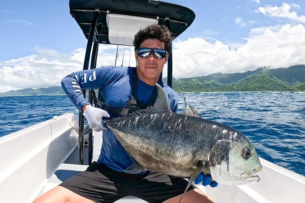 a man sitting on a boat holding a large fish