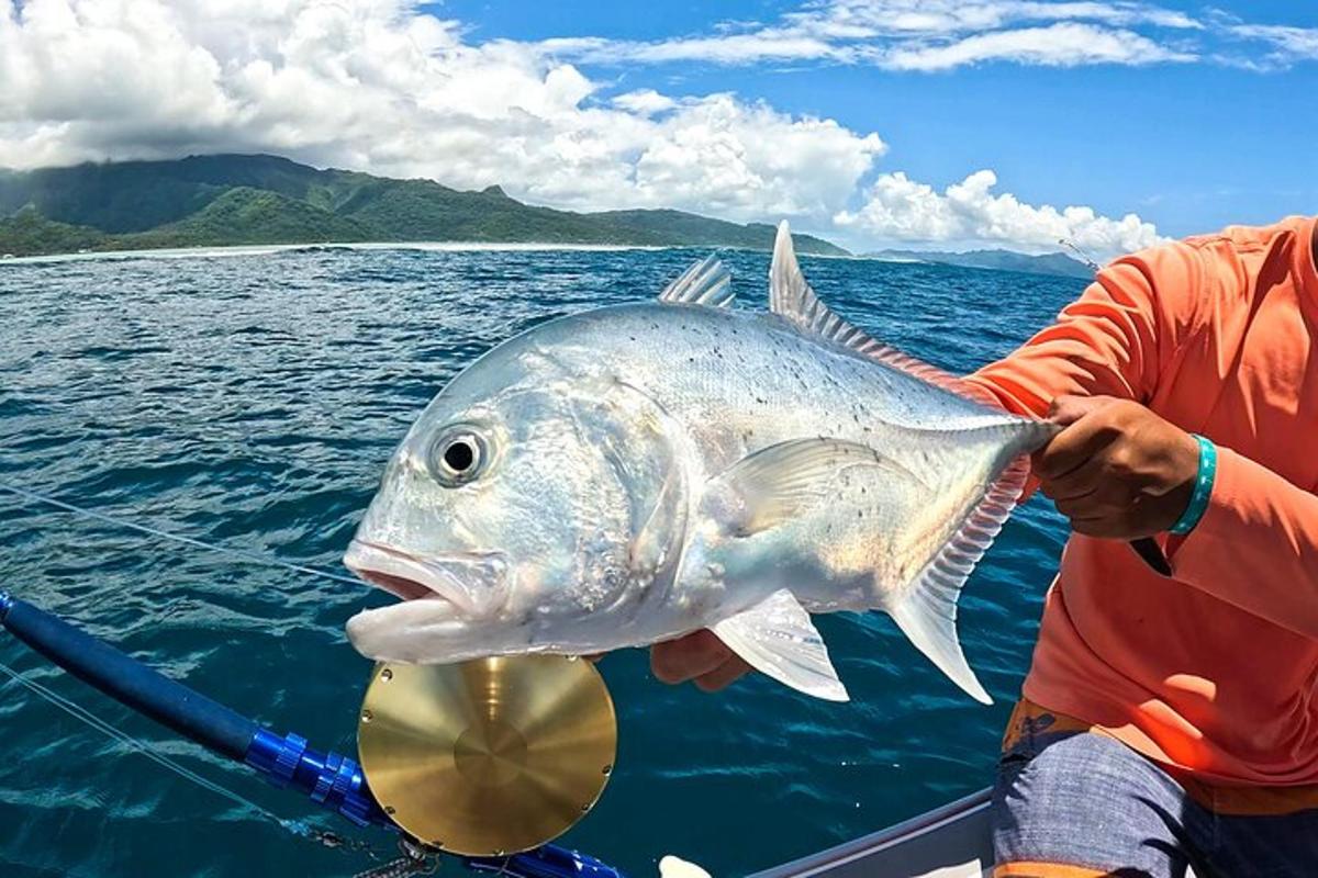 a man holding a large fish in front of a boat