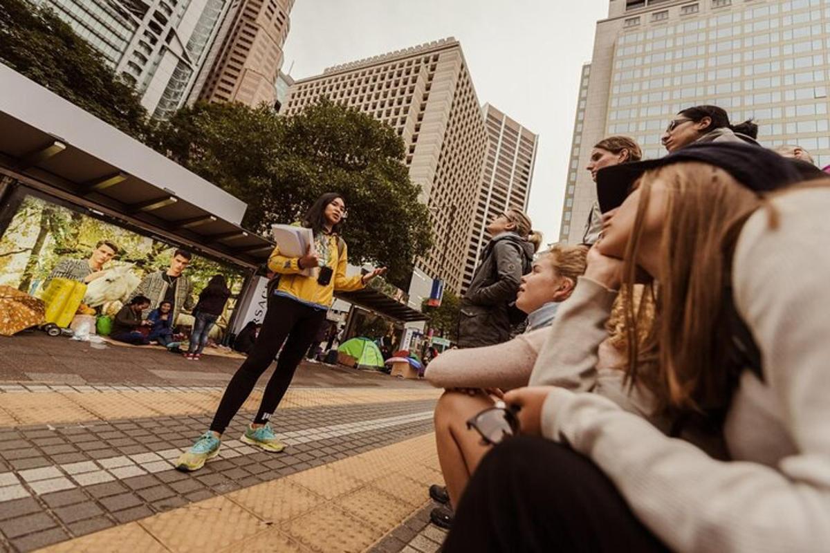 a group of people sitting on a sidewalk in a city