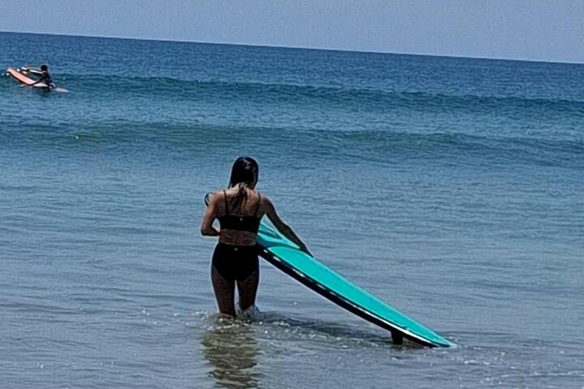 o femeie care stă în ocean ținând o placă de surf