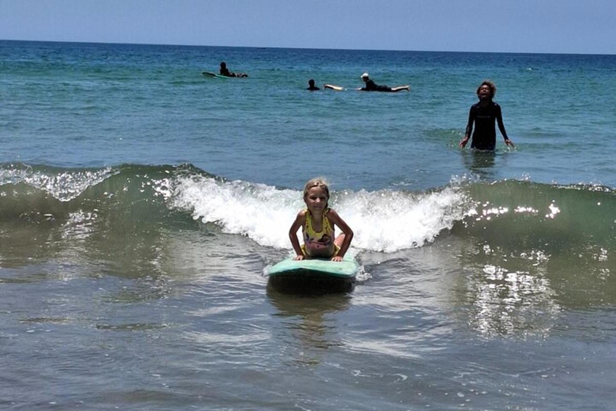 o fetiță stând pe o placă de surf în ocean