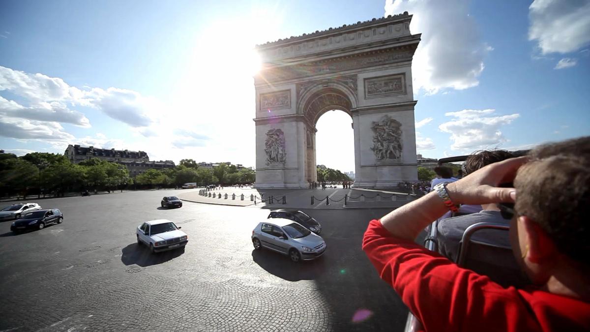 a person taking a picture of cars in front of the arch