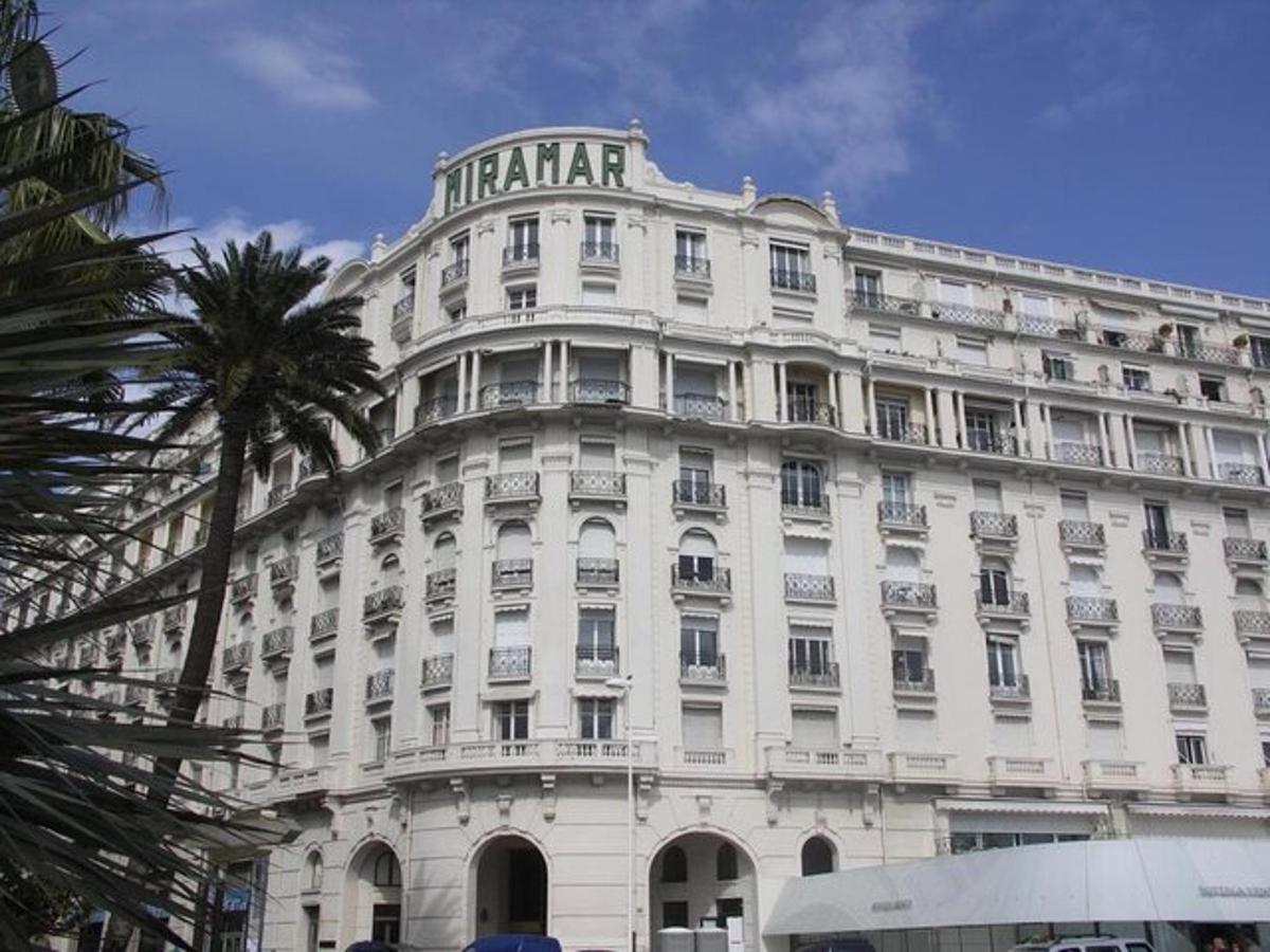 a large white building with a palm tree in front of it