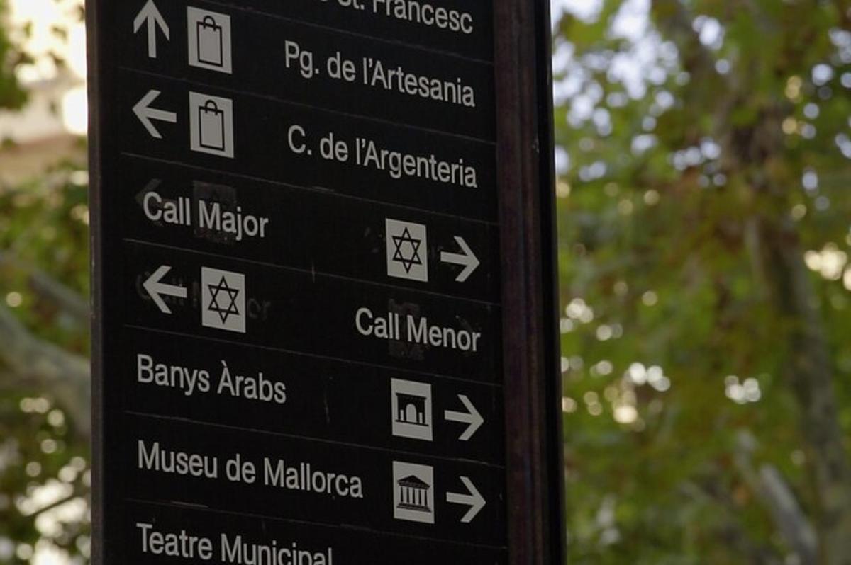 uma placa preta com setas em um poste