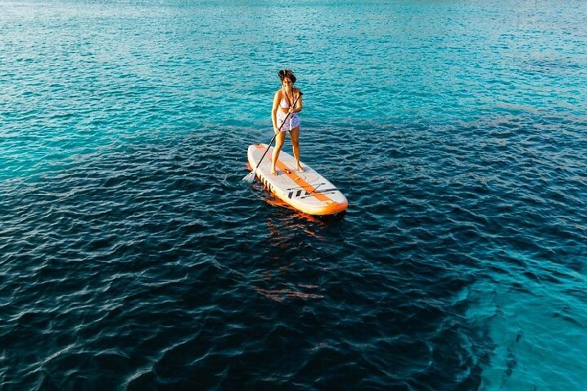 žena stojaca na oranžovej paddleboarde vo vode