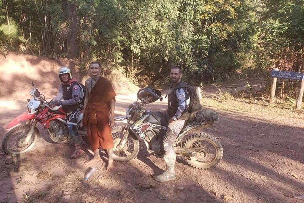 a group of three men standing next to a motorcycle