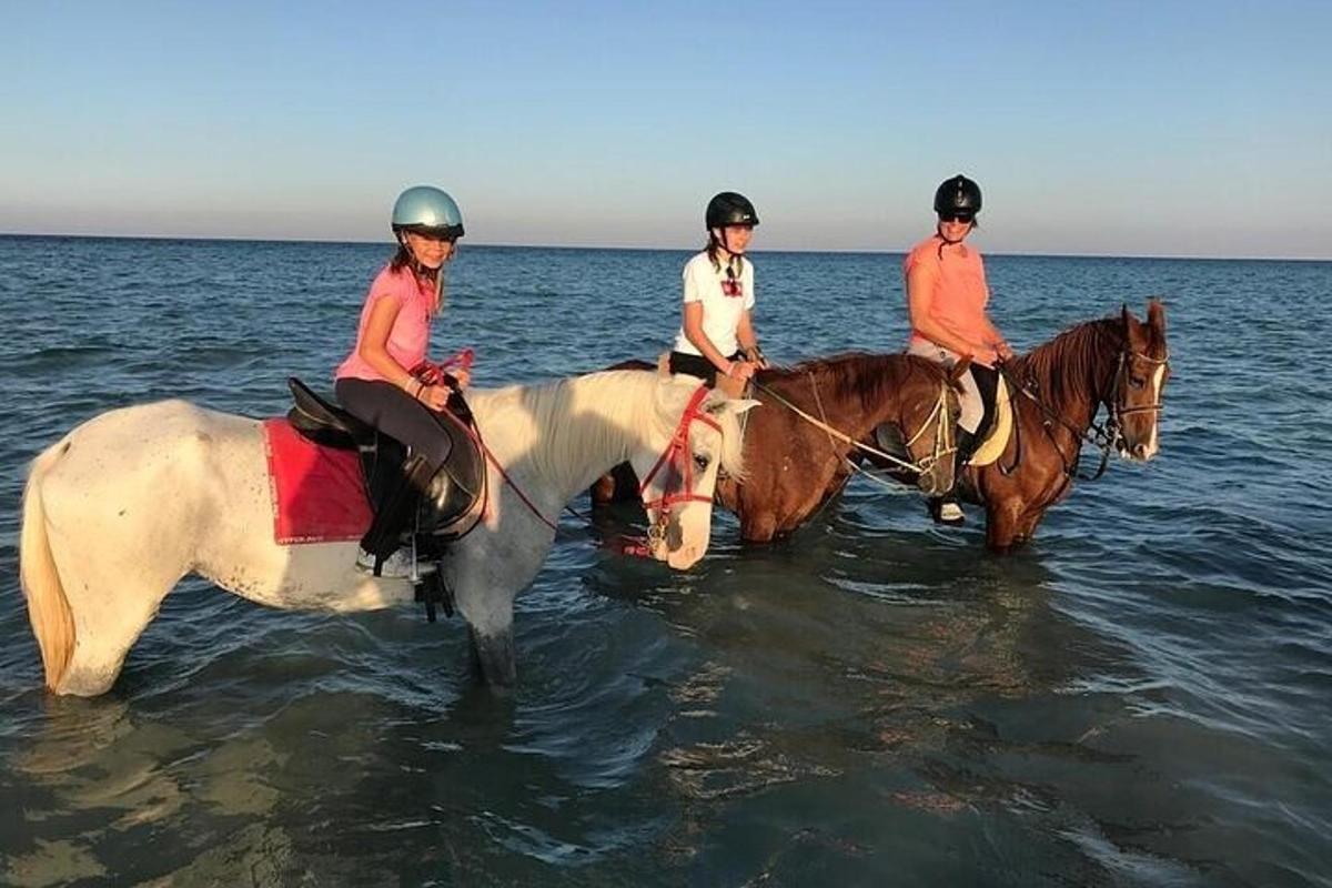 Tres personas montan a caballo en el agua.