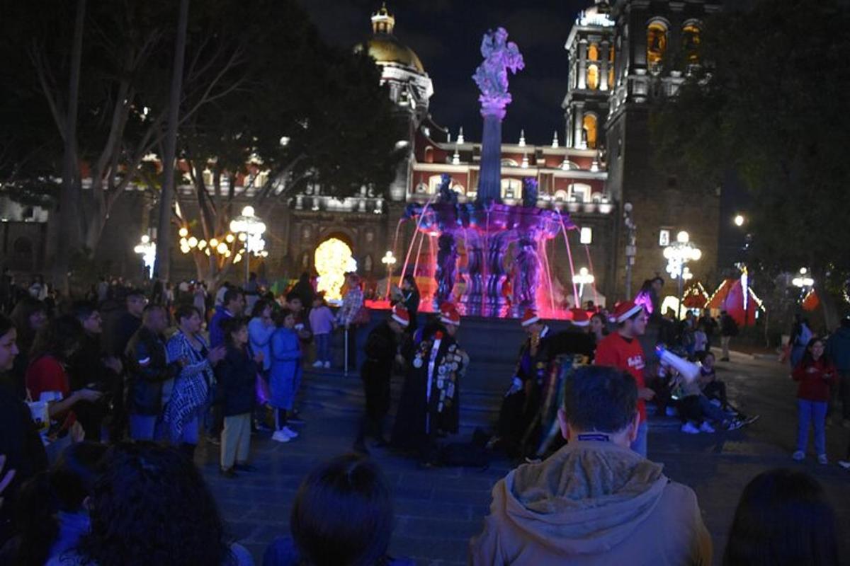 a crowd of people standing around a fountain at night