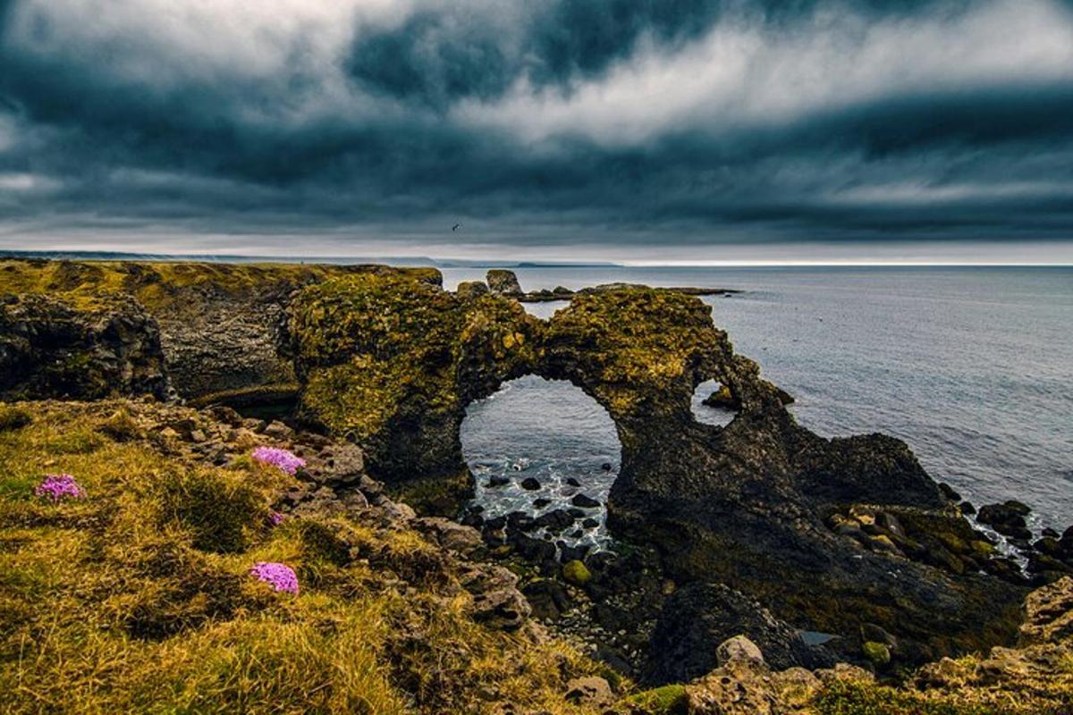 a stone arch on the side of the ocean