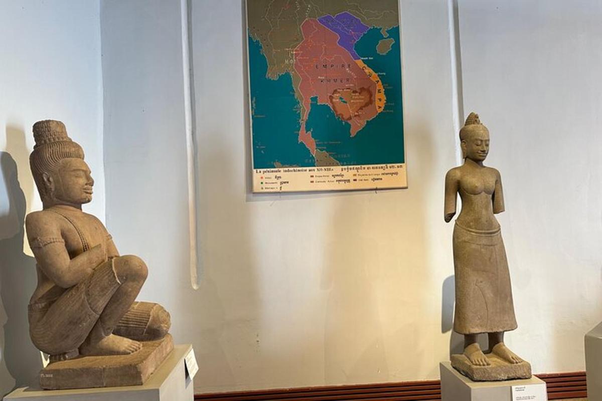 due statue in un museo con una mappa sul muro