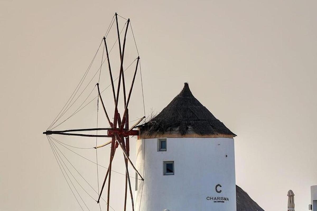 ein weißer Leuchtturm mit einer Windmühle davor