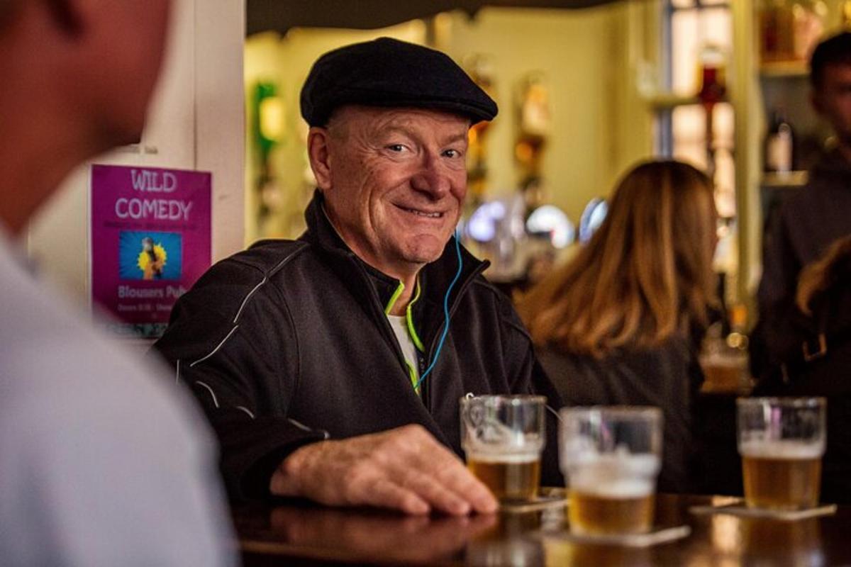 an older man sitting at a bar with glasses of beer
