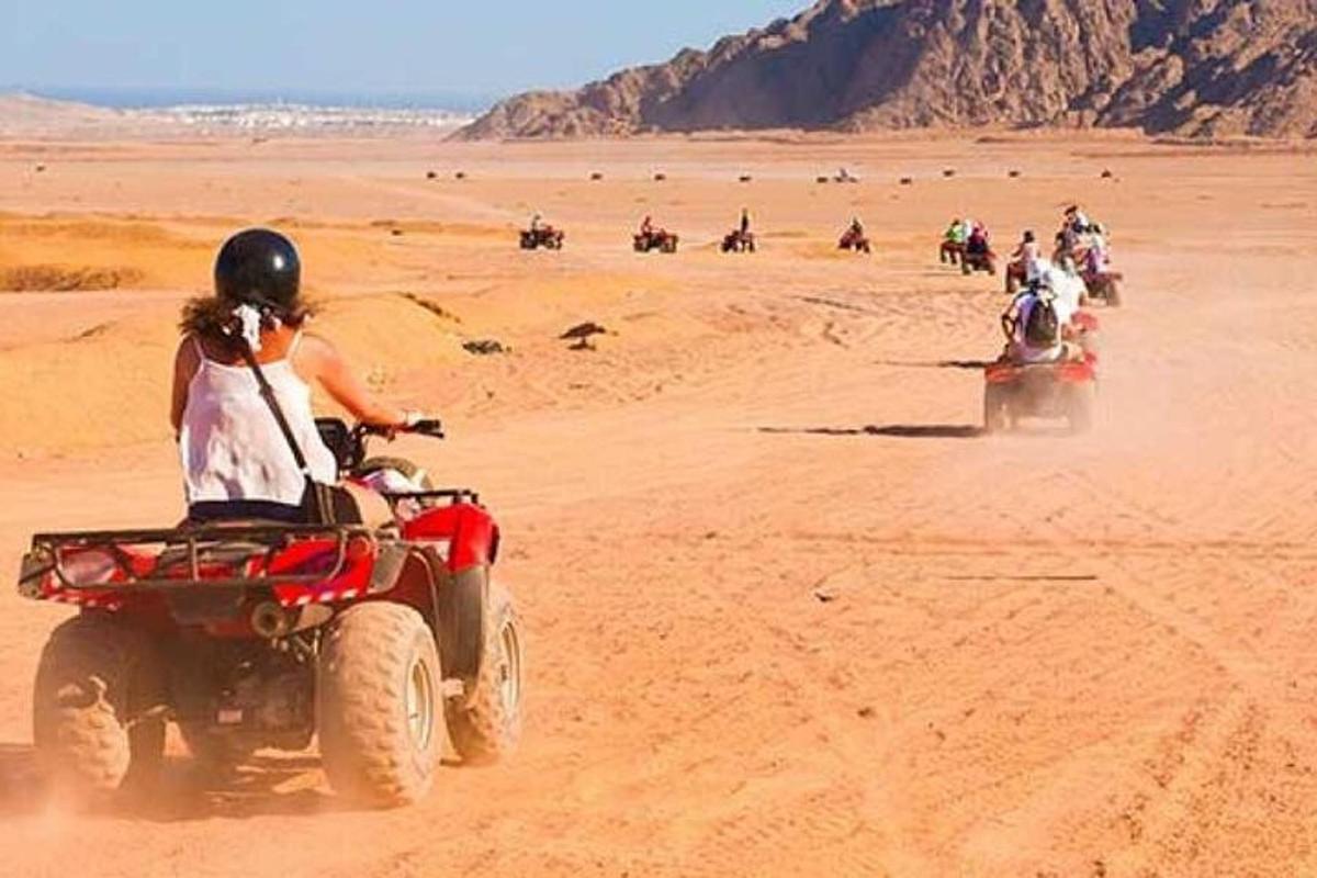 un grup de persones conduint quads al desert