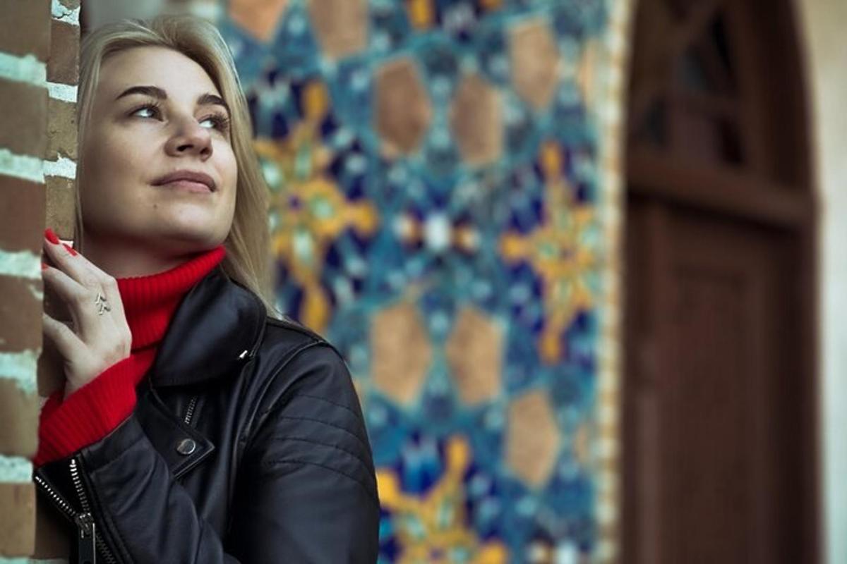 žena v kožené bundě opřená o zeď