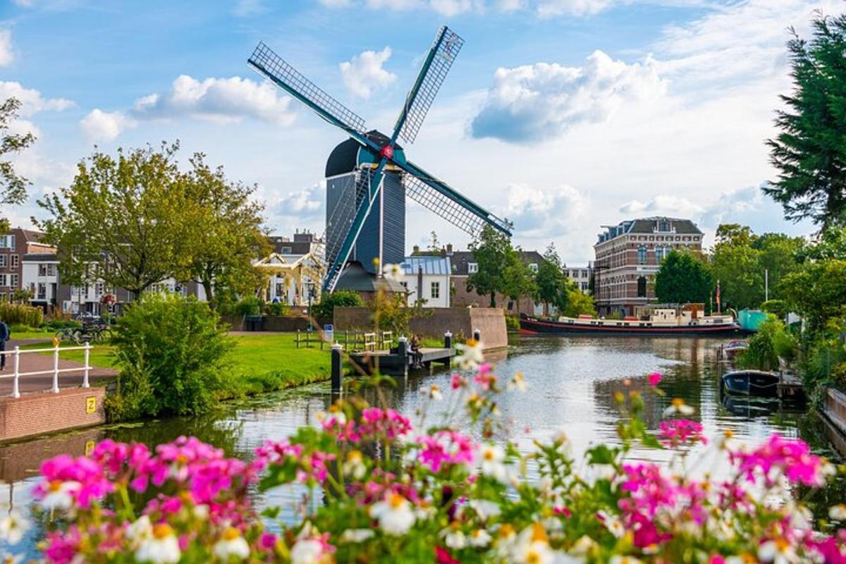 a windmill and flowers in front of a river