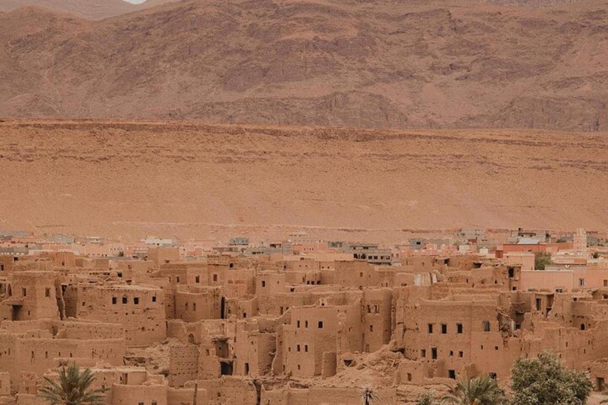 uma vila no deserto com uma montanha ao fundo