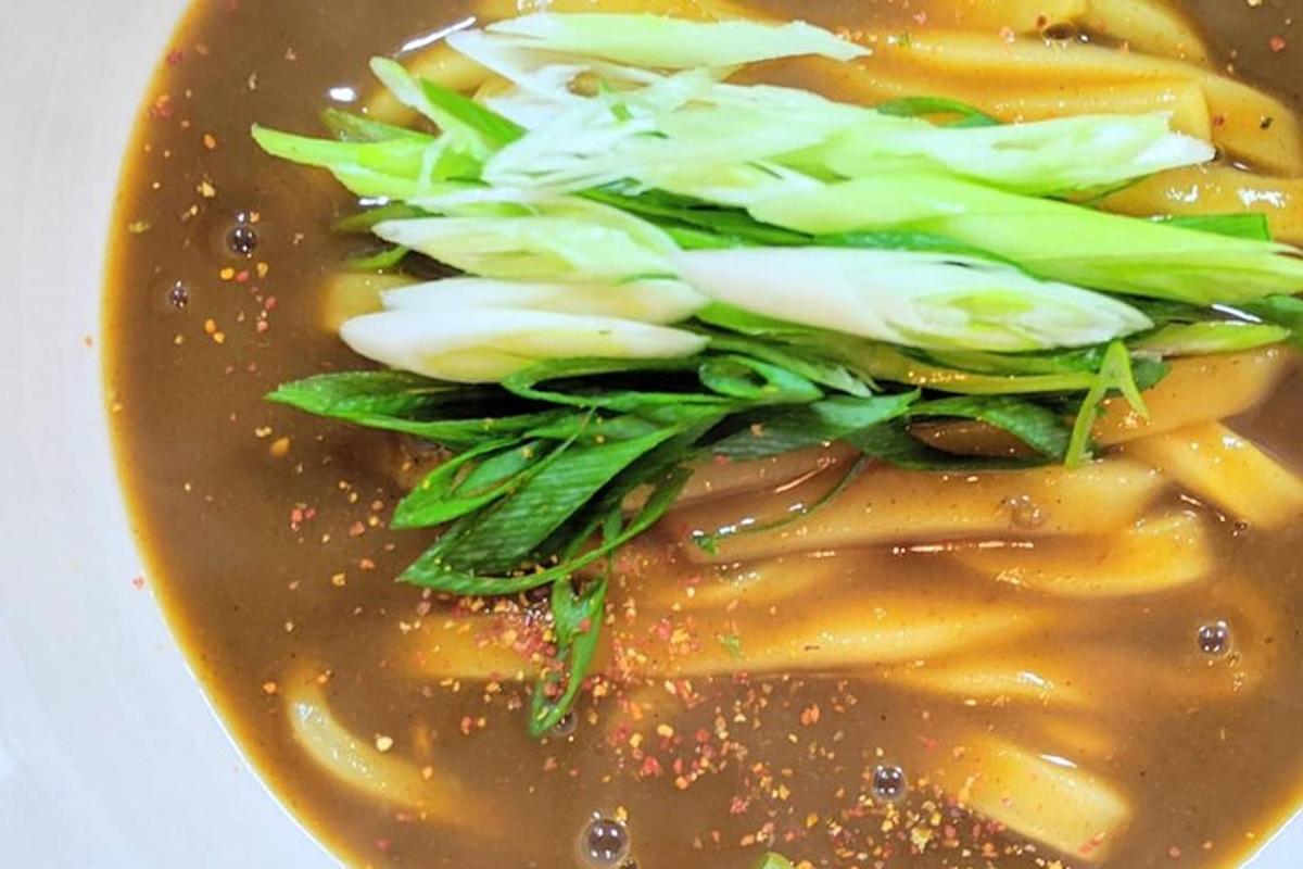 a bowl of soup with greens and onions in it