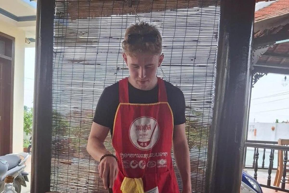moški v rdečem predpasniku stoji pred oknom
