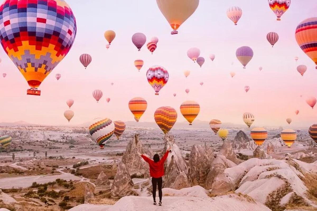 un uomo in piedi su una roccia con palloncini nel cielo