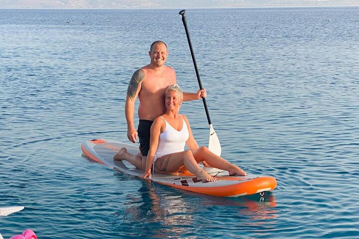 moški in ženska sedita na deski za veslanje v vodi