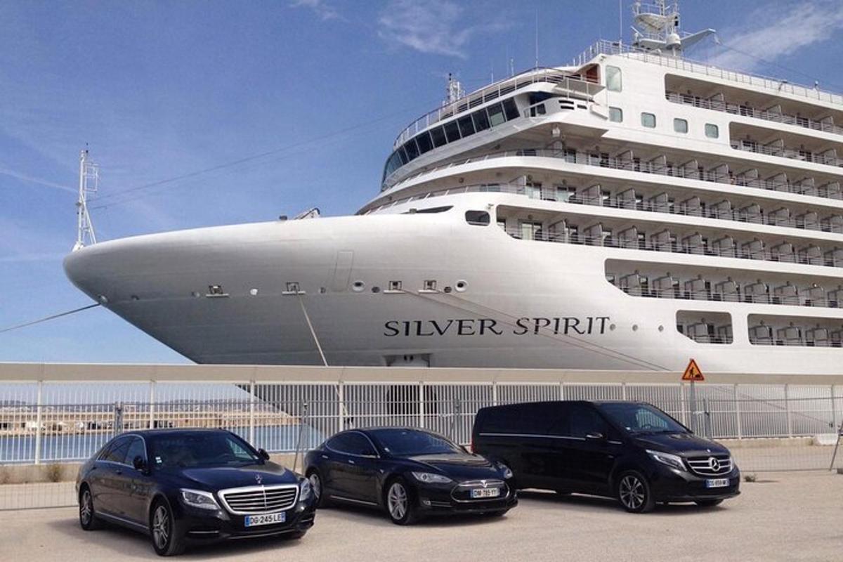 tre auto parcheggiate davanti a una nave da crociera