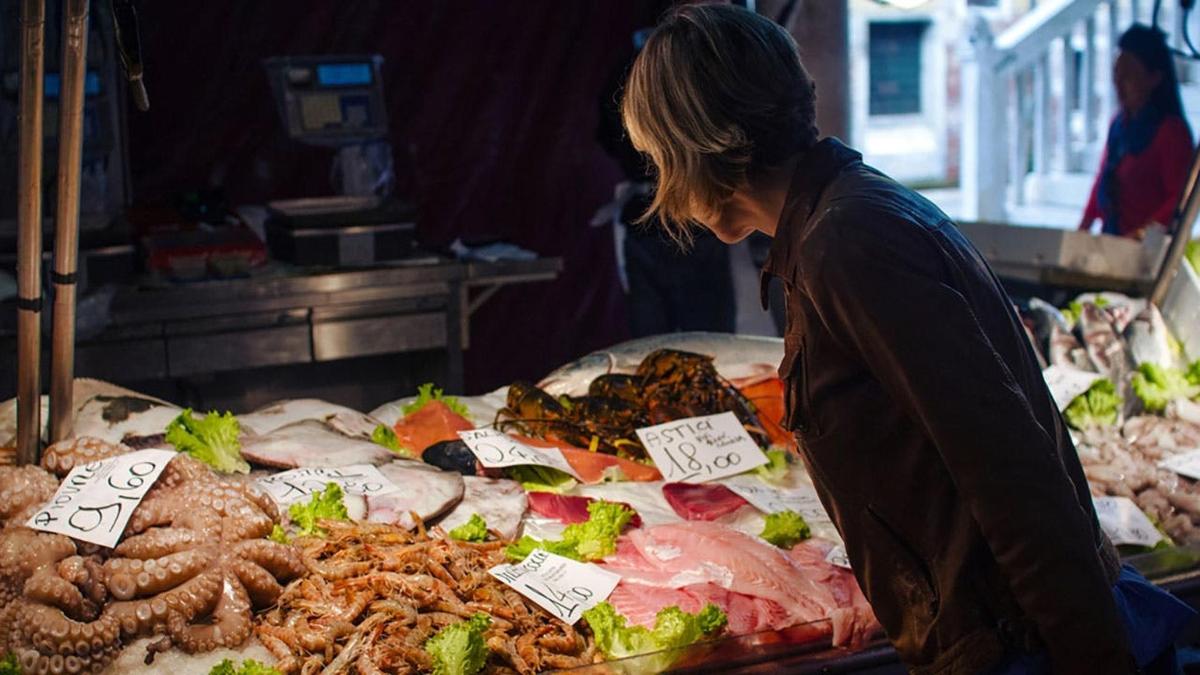eine Frau steht vor einer Auslage mit Meeresfrüchten