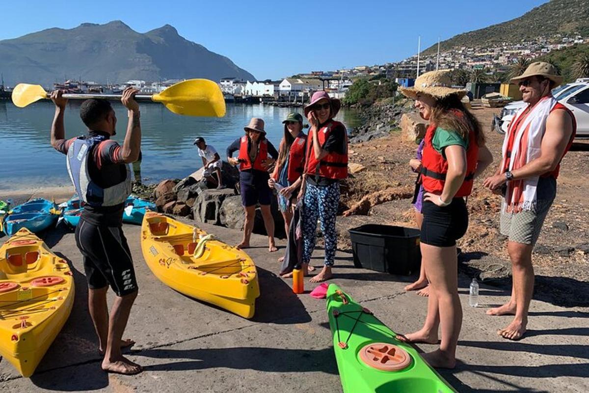 a group of people standing on a beach with kayaks