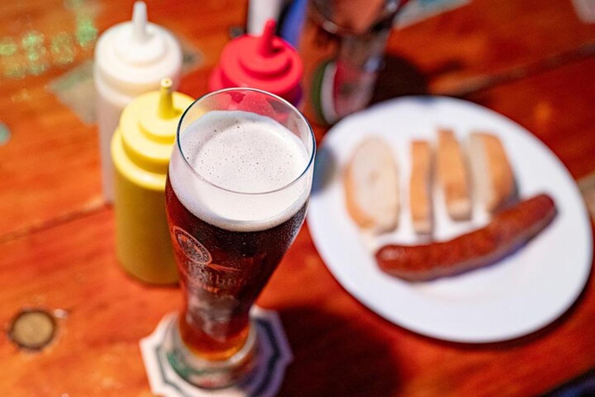 segelas bir di sebelah pinggan berisi hot dog