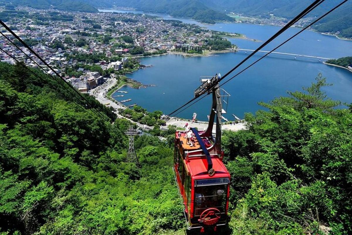 một chiếc cáp treo màu đỏ bay qua một ngọn đồi với một thành phố