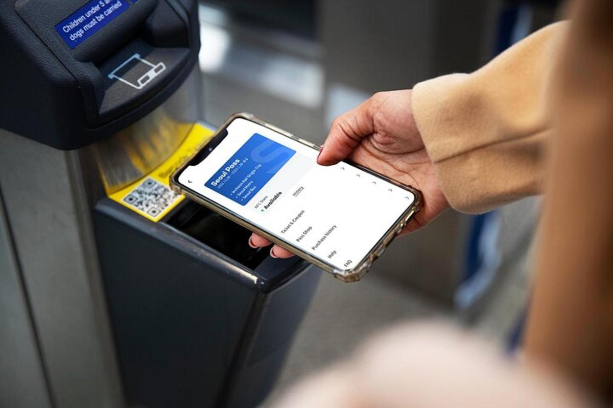osoba držící mobilní telefon u parkovacího automatu