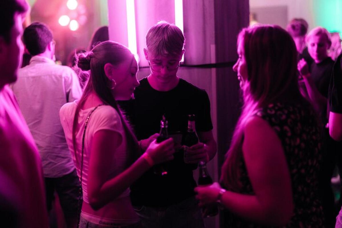 skupina lidí stojících v místnosti s lahvemi vína