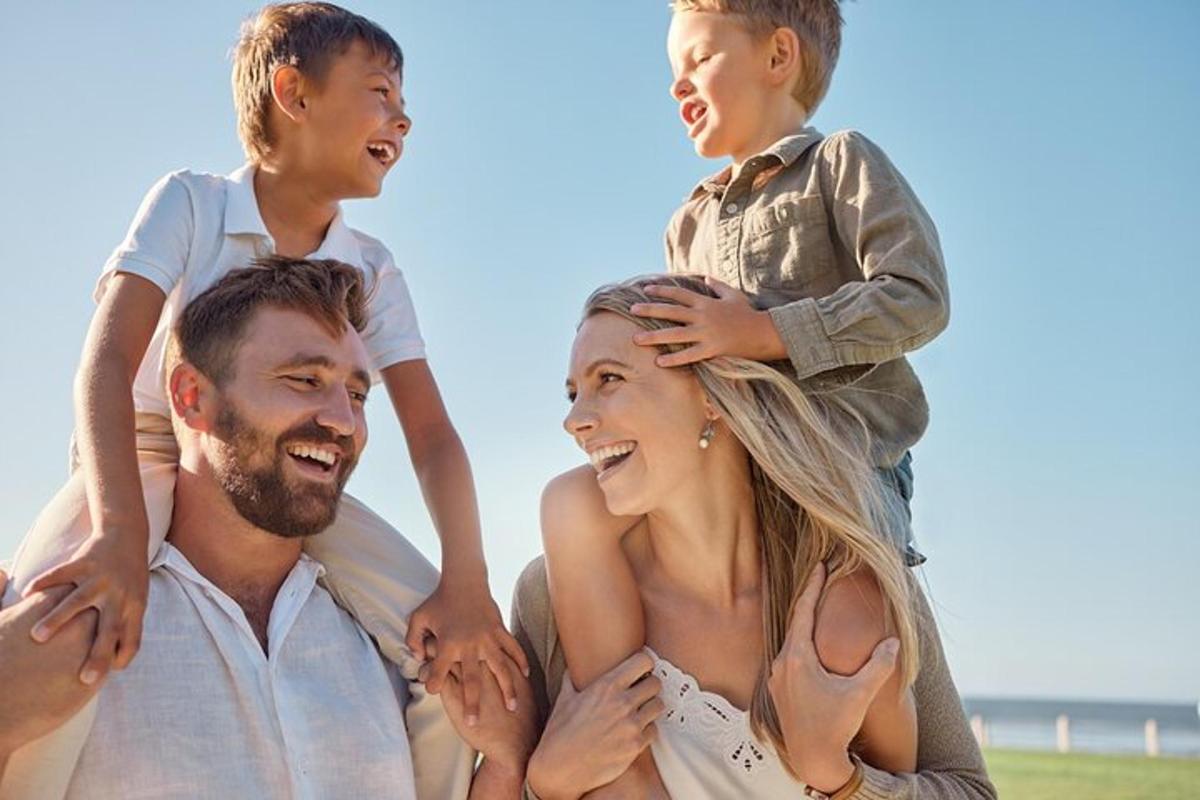 Una familia parada en la playa con su hijo sobre sus hombros