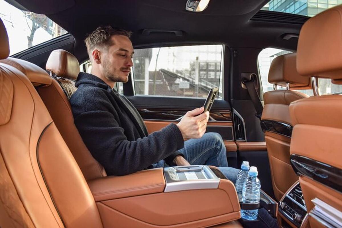 un uomo seduto sul sedile posteriore di un'auto che usa un tablet