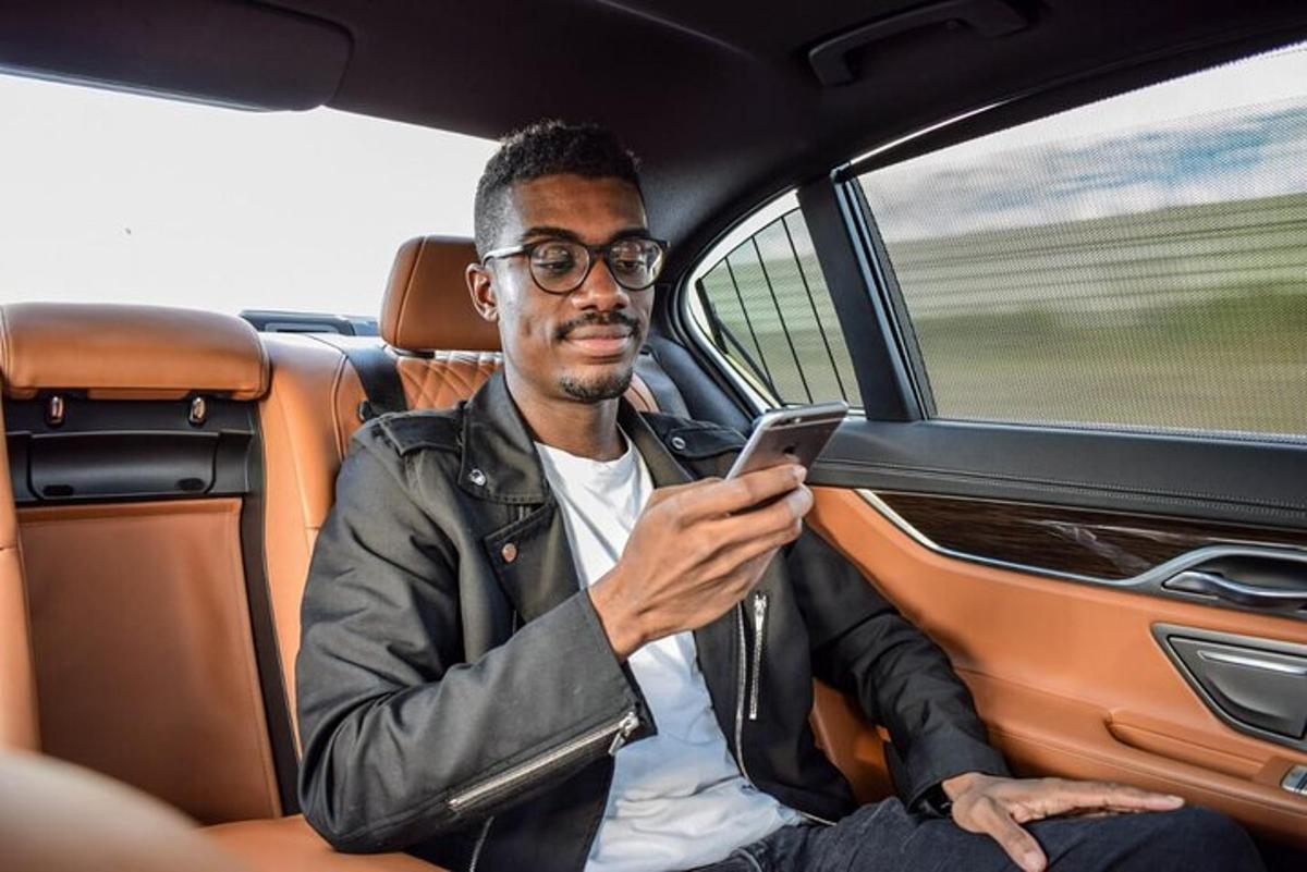 un uomo seduto in macchina che guarda il suo cellulare