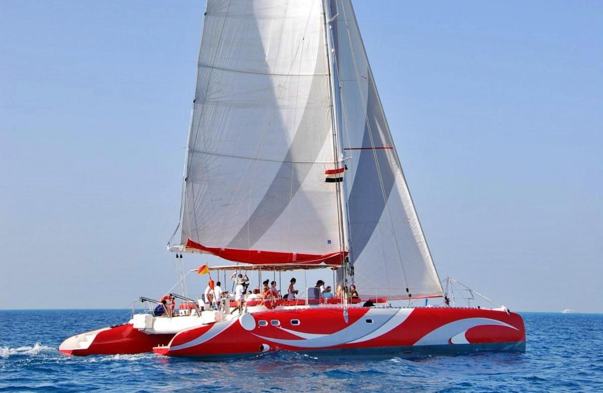 a red and white sail boat in the water