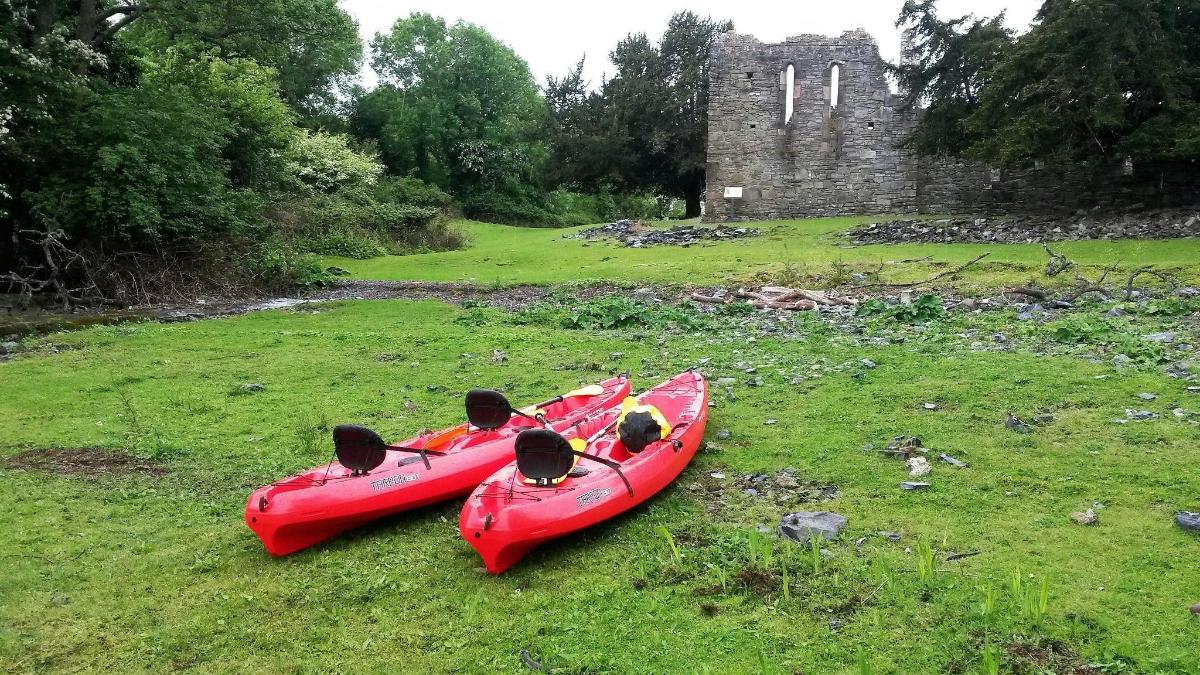 dos caiacs vermells asseguts a l'herba prop d'un castell