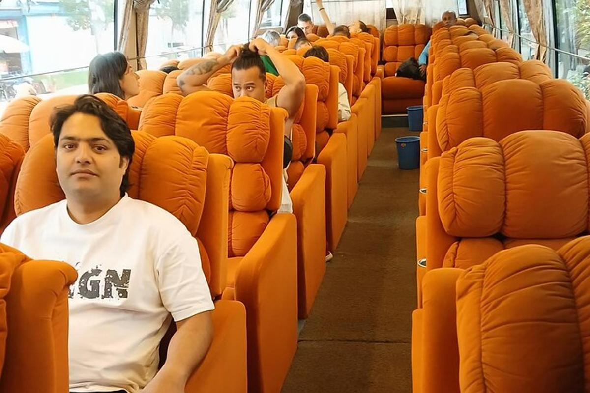 一名男子坐在公交车上的橙色座位上