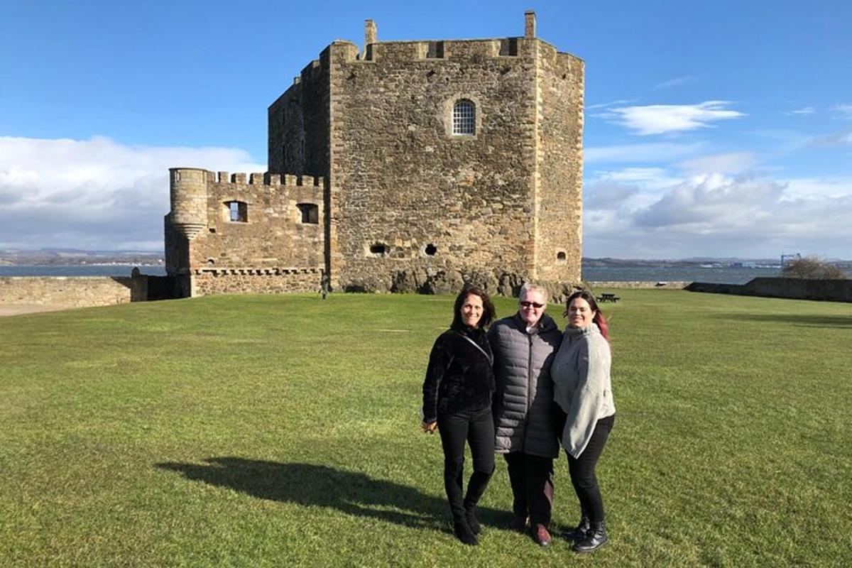 três pessoas em pé em frente a um castelo