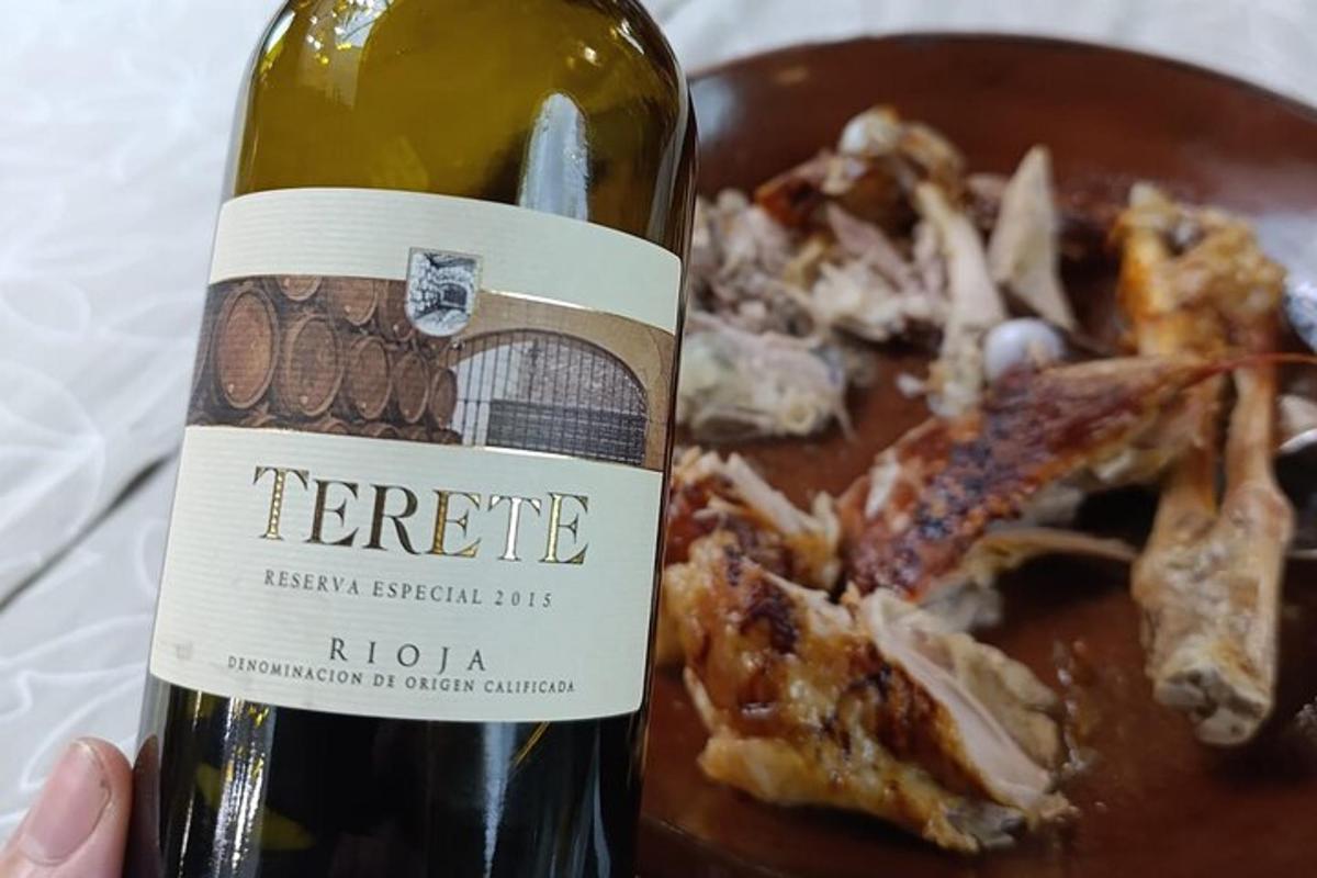 oseba, ki drži steklenico vina poleg krožnika s hrano