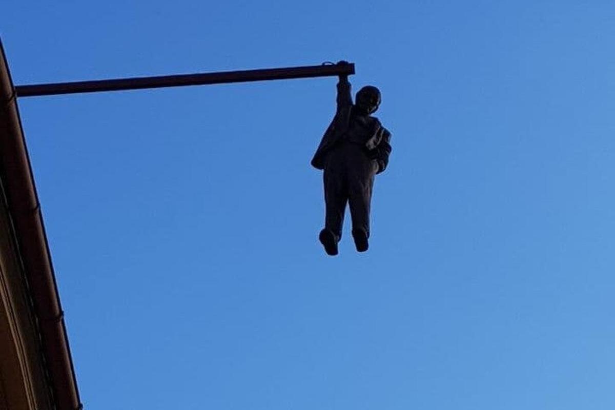 muž visící z tyče na obloze