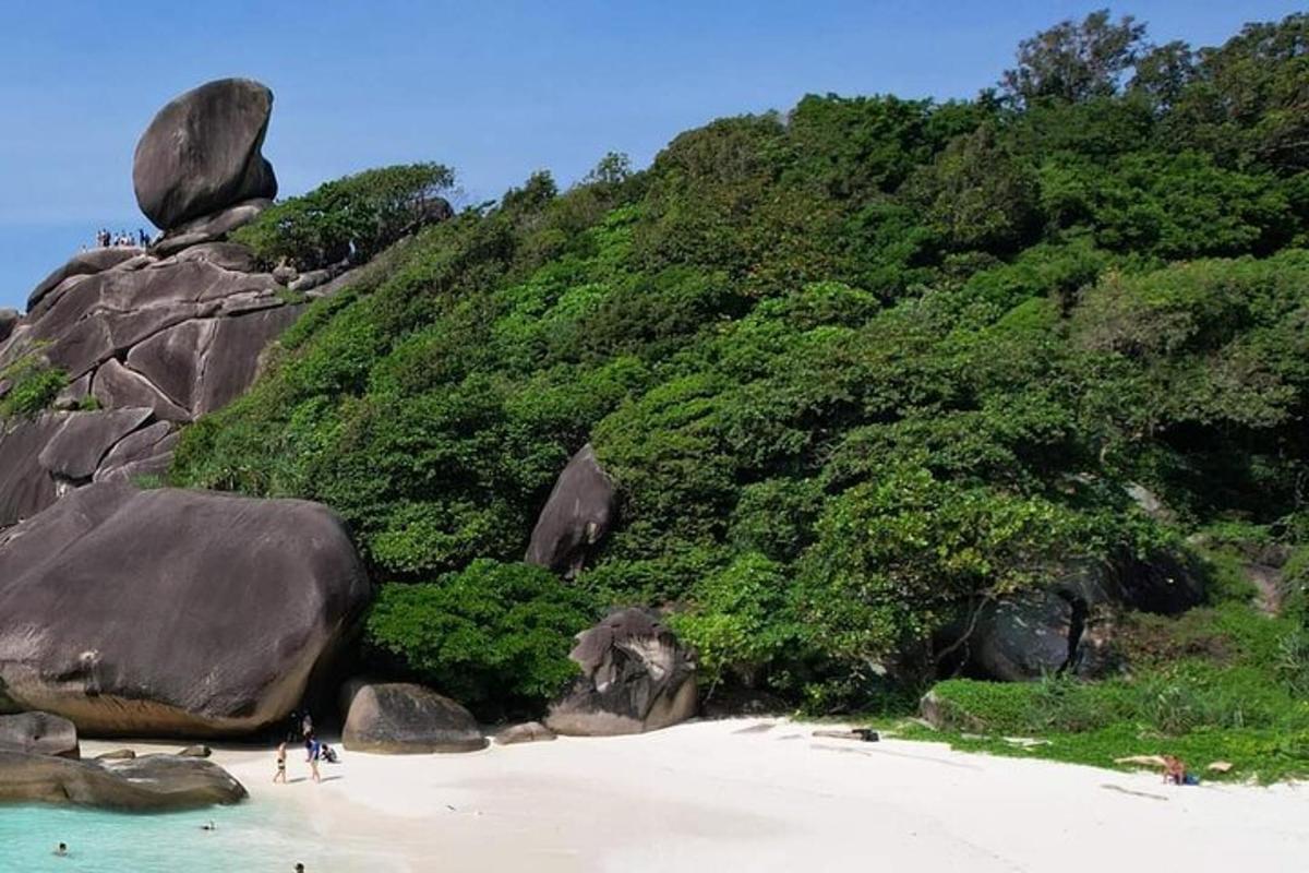 two people standing on a beach next to a mountain