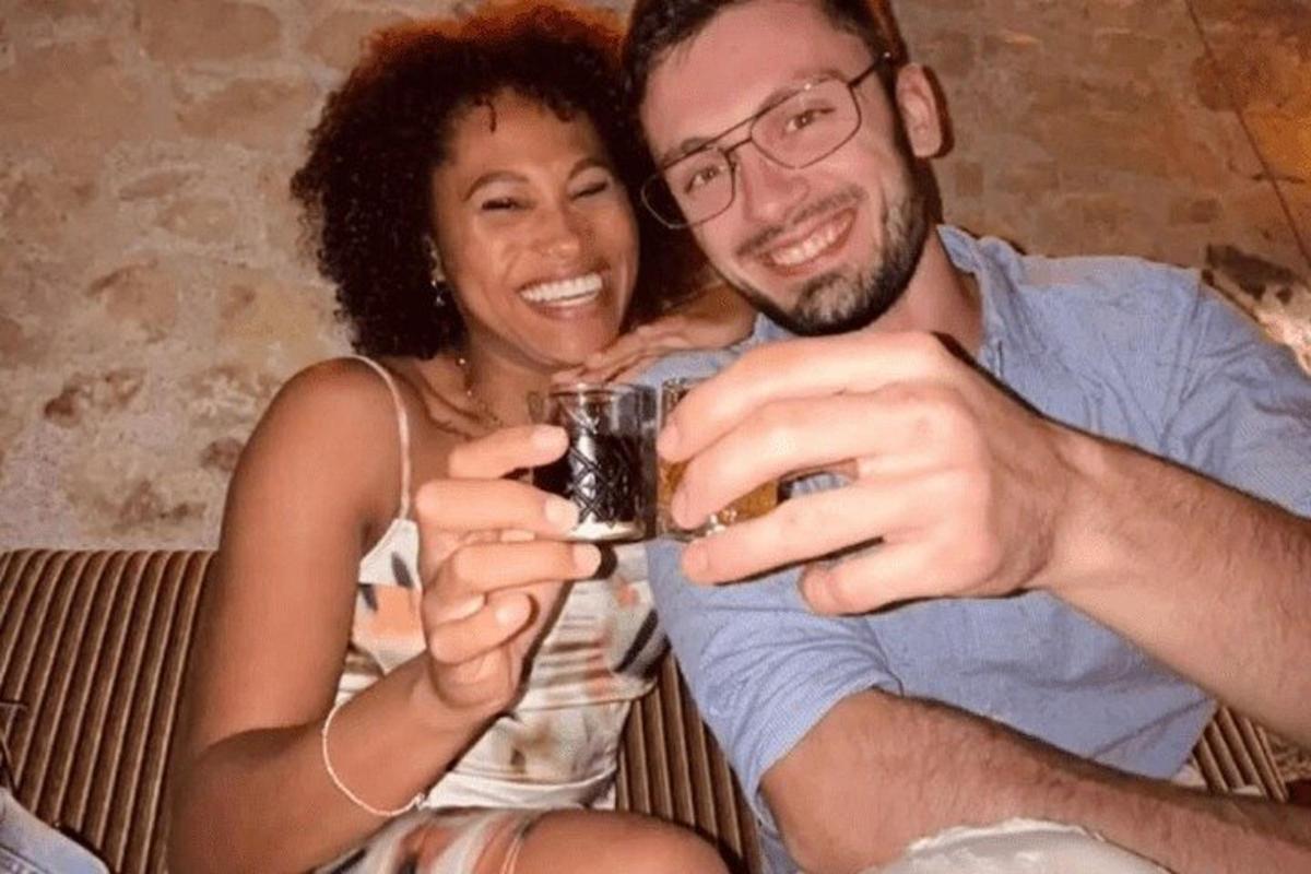Un hombre y una mujer sentados en un sofá sosteniendo una bebida